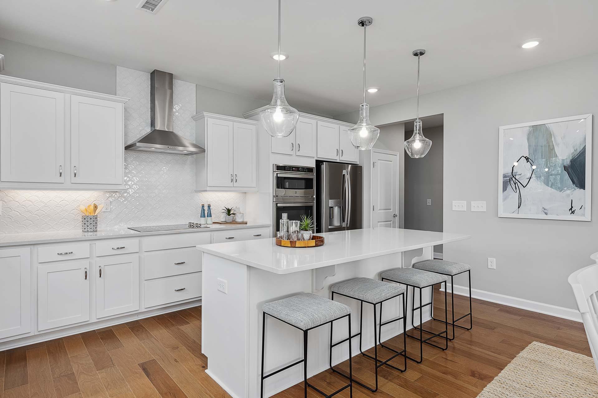 Modern white kitchen with large island, subway tile backsplash, stainless appliances at Highland Forest in Fuquay-Varina NC