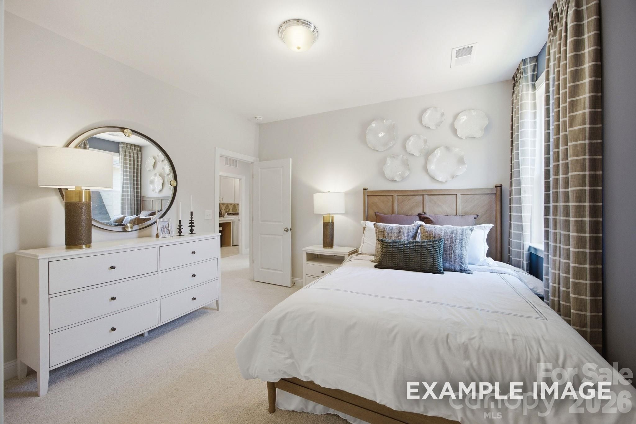 Bright guest bedroom with white dresser and wood-frame bed in The Hickory B II floor plan, Windgate, Mooresville, NC.