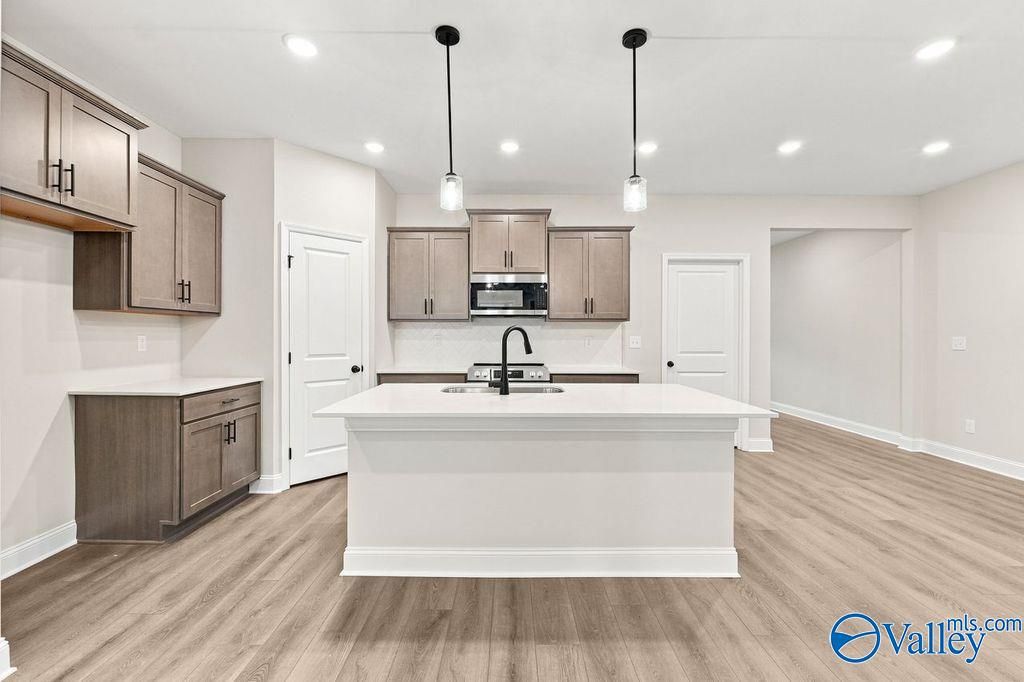 Modern kitchen with white island and gray cabinetry in The Camilla C floor plan at The Retreat at Cain Park, Hartselle, AL.