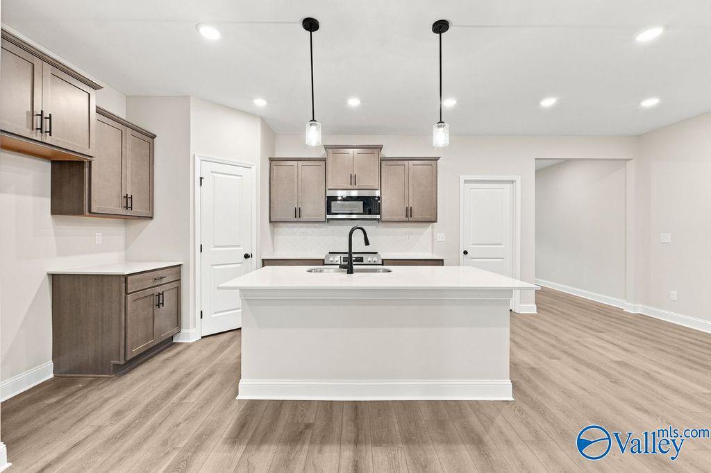 Modern kitchen with white island and gray cabinetry in The Camilla C floor plan at The Retreat at Cain Park, Hartselle, AL.