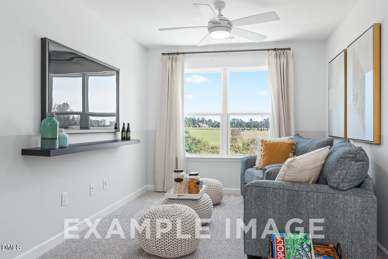 Bright loft living room with gray sofa, wall-mounted TV, and scenic views in Davidson Homes The Ash C, Lillington, North Carolina