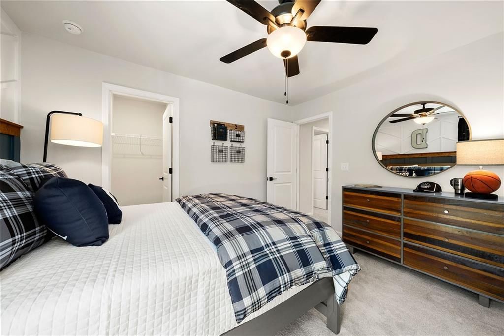 Cozy boy's bedroom with plaid bedding, wooden dresser, round mirror, basketball decor in 5-bedroom Willow B home, Riverwood, Dallas, GA