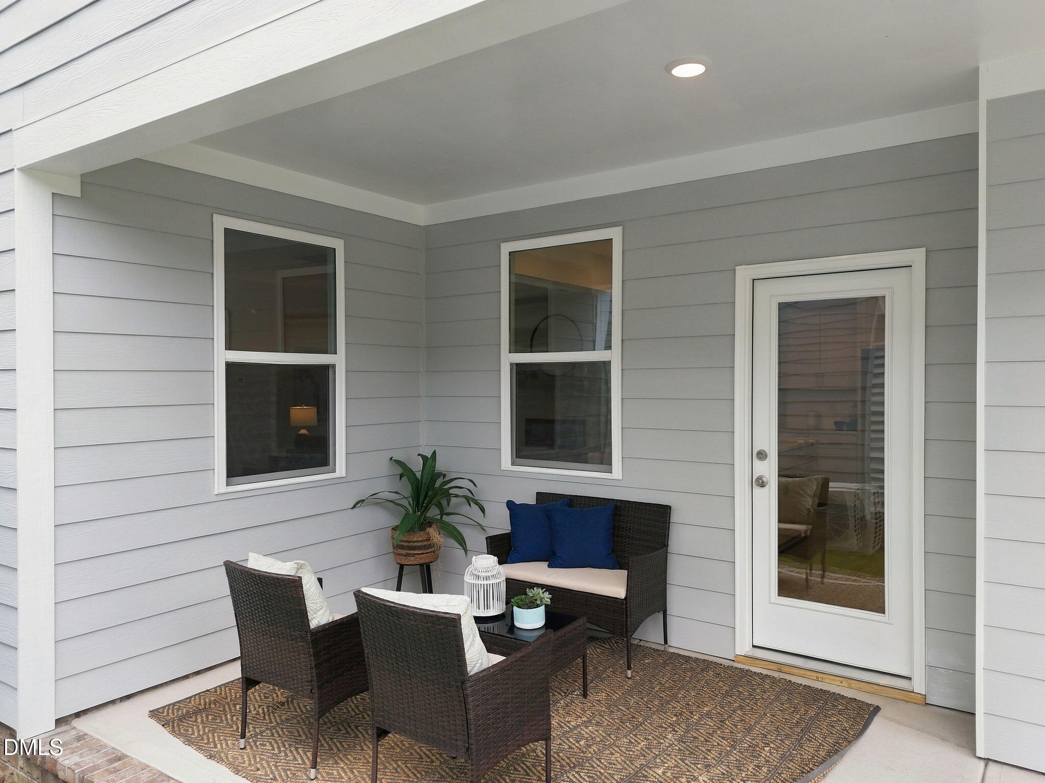 Covered patio with wicker seating and glass-panel door at Davidson Homes The Jordan C in Forestville Yard, Knightdale, North Carolina