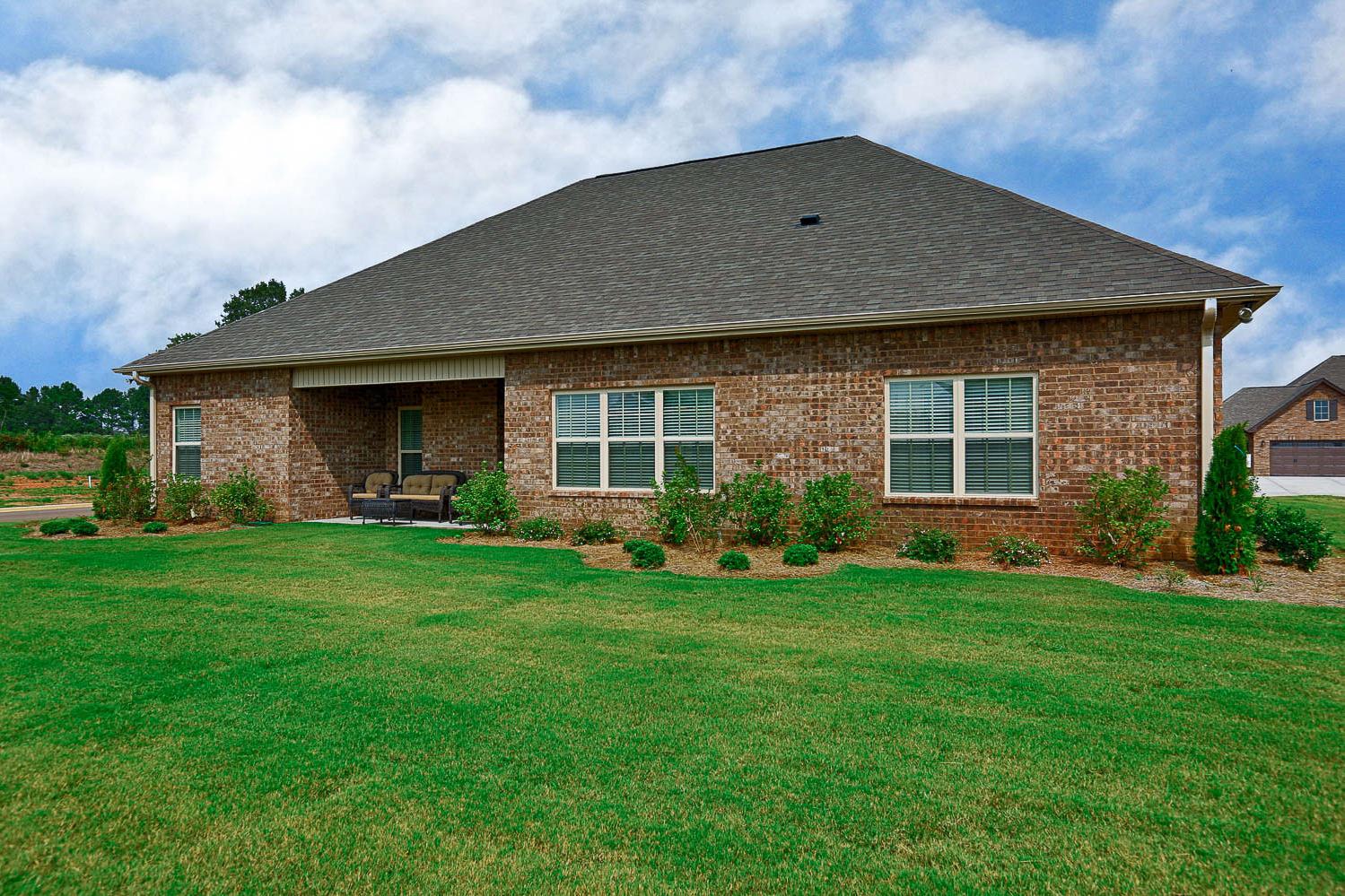 Side view of The Finleigh 3-bedroom single-story home with brick facade, covered porch, and manicured lawn in Meridianville, Alabama