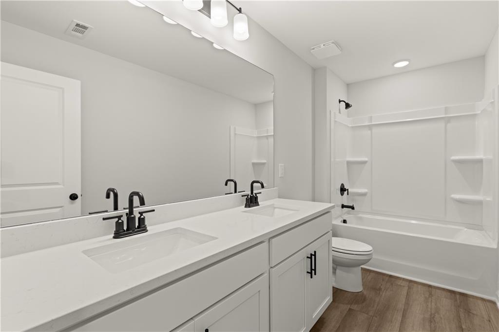 Modern bathroom with dual vanity, white cabinetry, and shower-tub combo in The Hartwell A floor plan, The Bluffs, Canton.