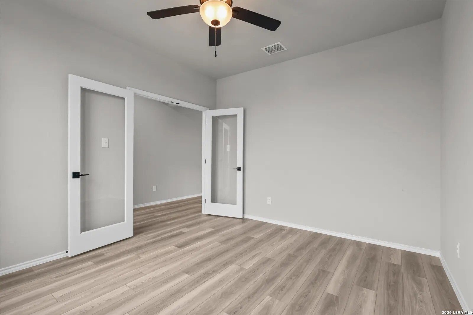 Bright home office with glass French doors and wood-look flooring in The Glenwood E plan, Comanche Ridge, San Antonio.