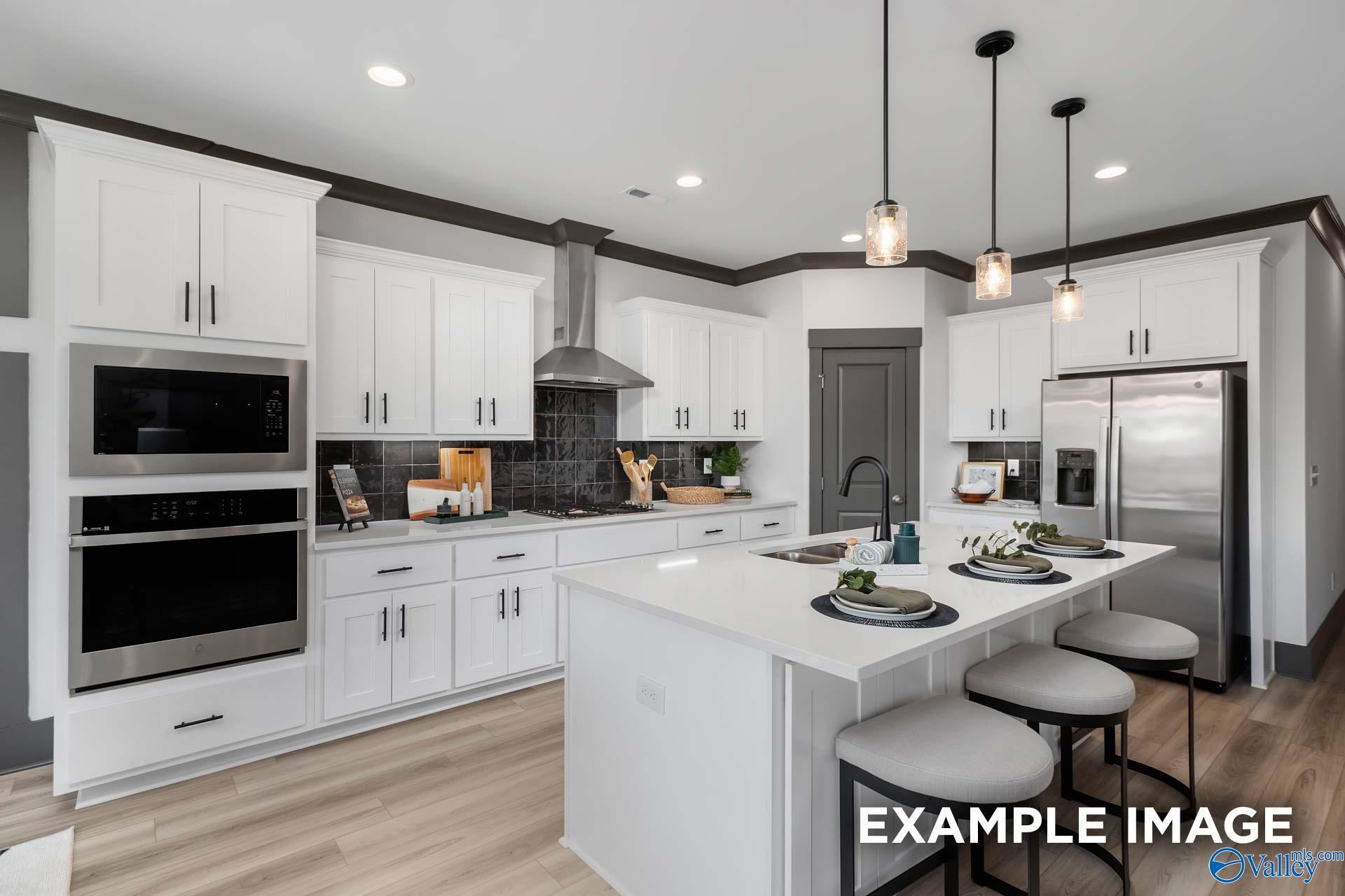 Modern kitchen with white cabinets, stainless steel appliances, large island and pendant lights in Davidson Homes The Rockford B, Madison AL