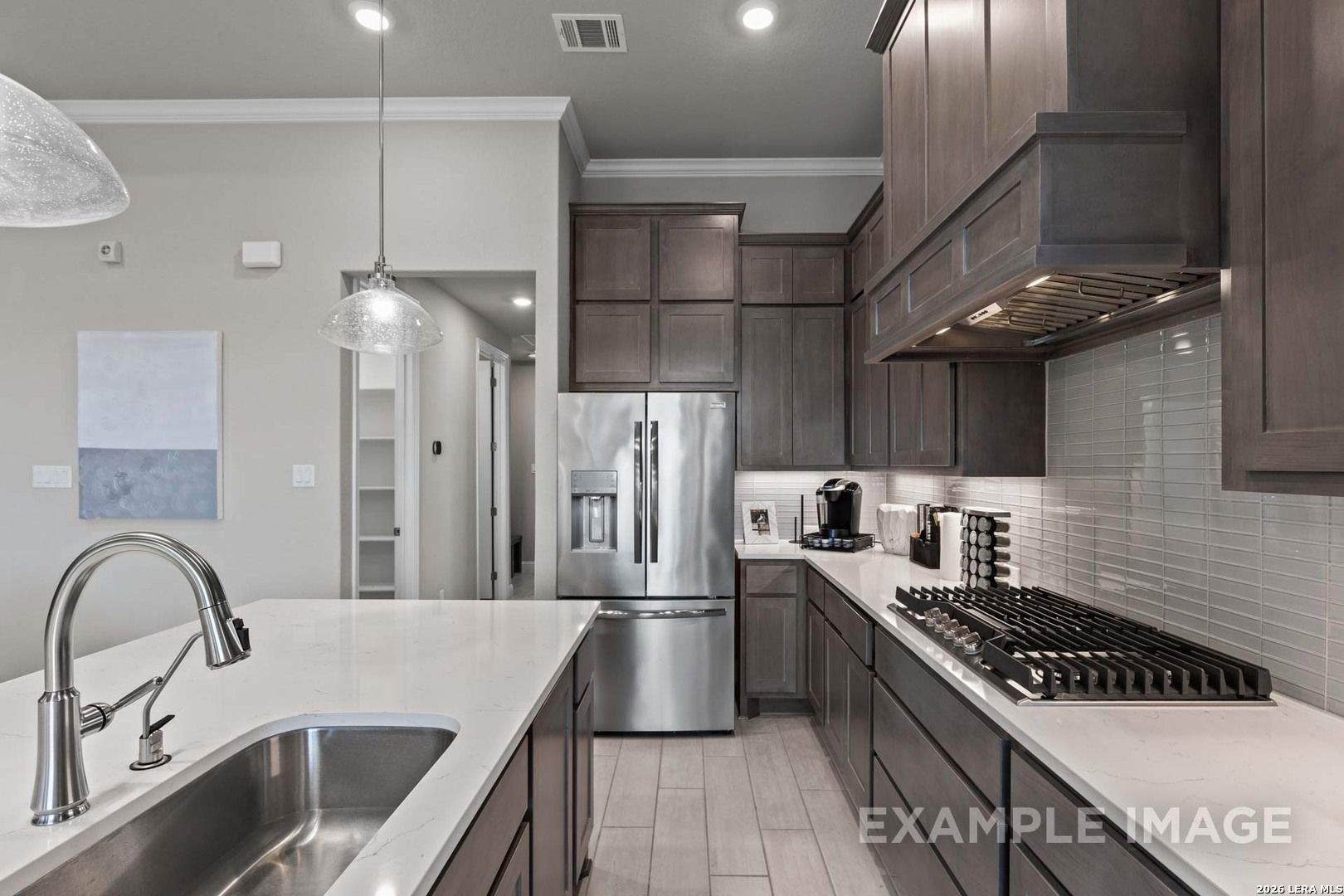 Modern kitchen with dark cabinets, stainless appliances, and quartz island in The Garner C plan at Potranco Oaks, Texas.