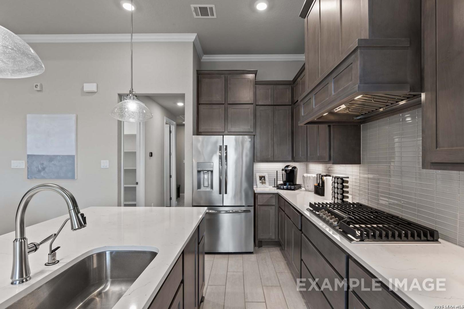 Modern kitchen with dark cabinets, stainless appliances, and quartz island in The Garner C plan at Potranco Oaks, Texas.