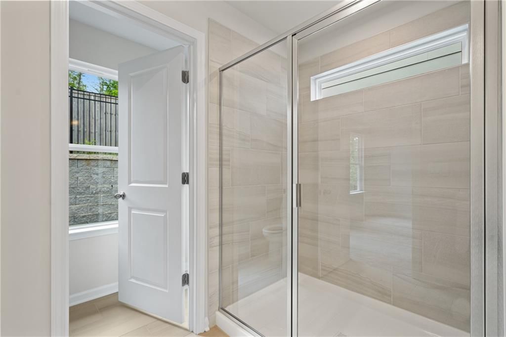 Modern glass shower with sliding doors and beige tile walls in master bathroom, Davidson Homes The Marion B, Kennesaw, GA