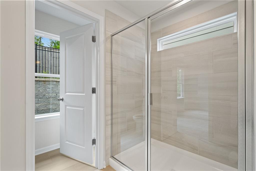 Modern glass shower with sliding doors and beige tile walls in master bathroom, Davidson Homes The Marion B, Kennesaw, GA