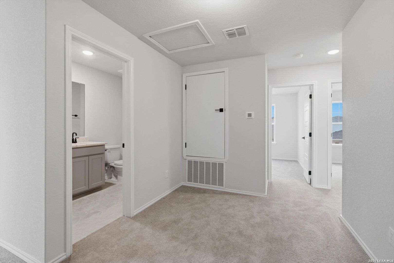 Upstairs carpeted hallway with doors to bedrooms and guest bathroom featuring vanity sink in Davidson Homes The Blanco C, San Antonio