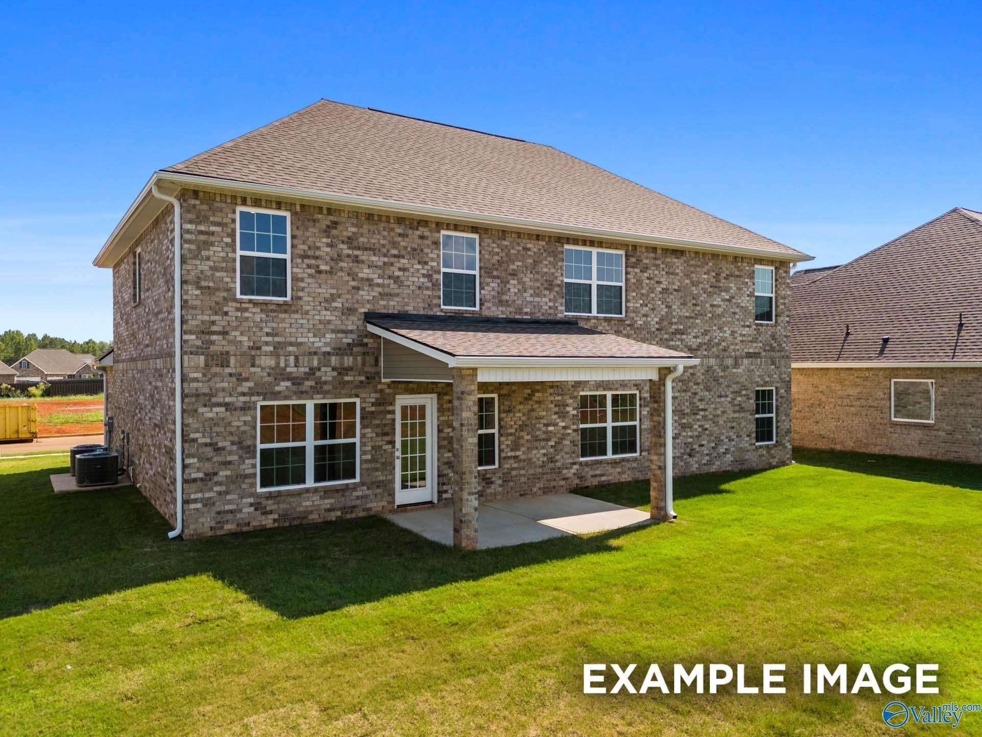 Brick 1.5-story Madison A home exterior with covered patio, French doors, and lush green lawn in Kendall Downs, Toney, Alabama