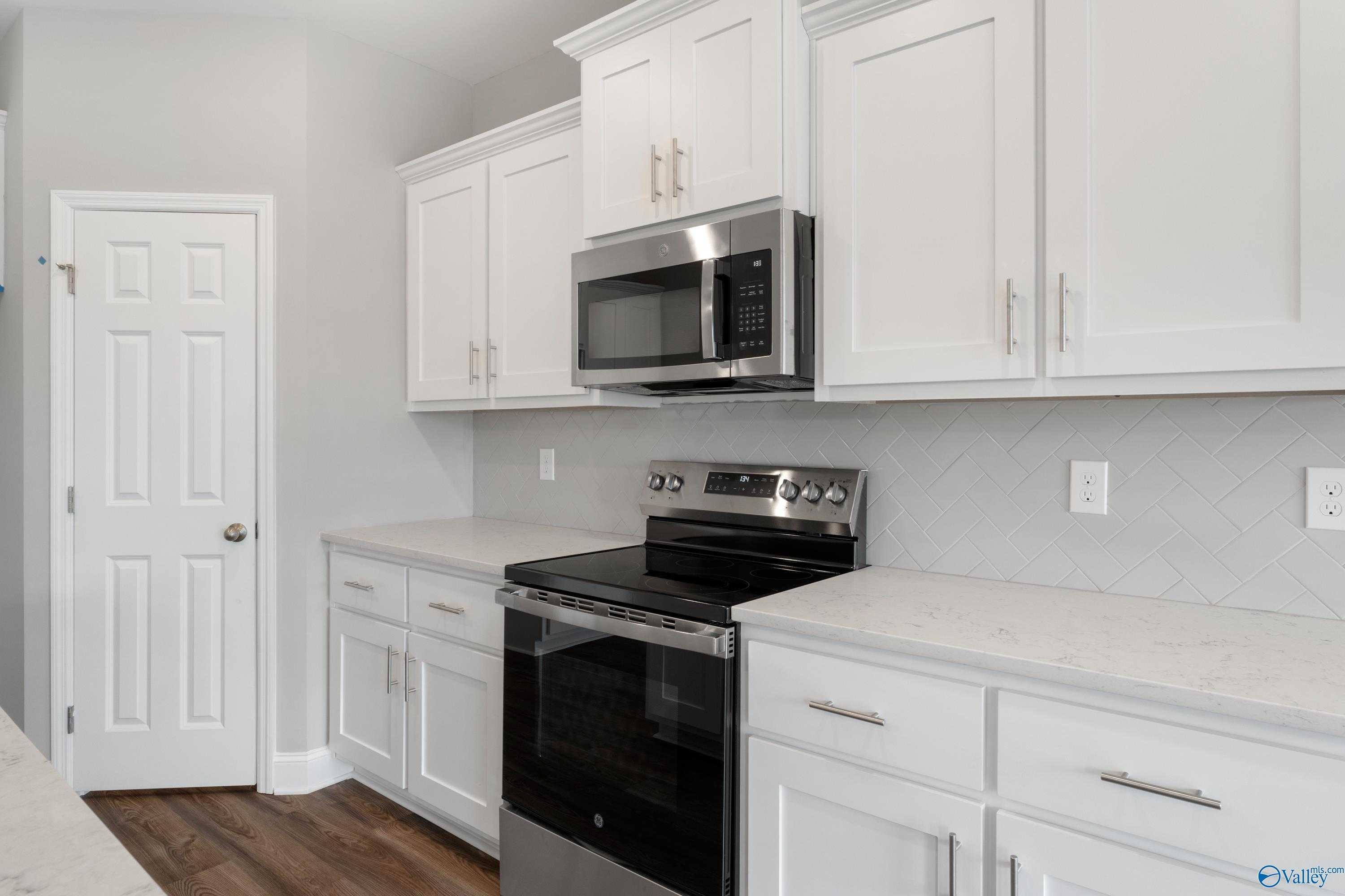 Modern kitchen featuring white shaker cabinets, stainless steel range and microwave, gray subway tile backsplash in The Aiken by Davidson Homes, Meridianville AL