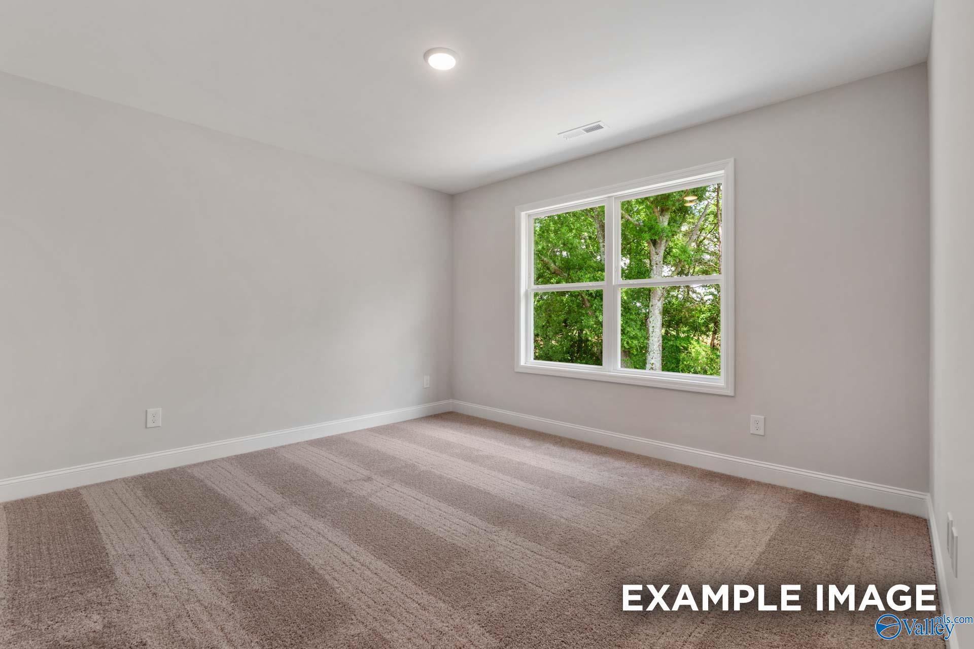Bright bedroom with neutral walls, plush carpet, and large window overlooking trees in Davidson Homes Shelby C, Meridianville AL