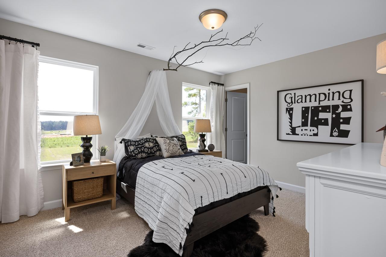Cozy glamping-themed bedroom with canopy bed, striped duvet, lamps and branch decor at Wellers Knoll in Lillington NC