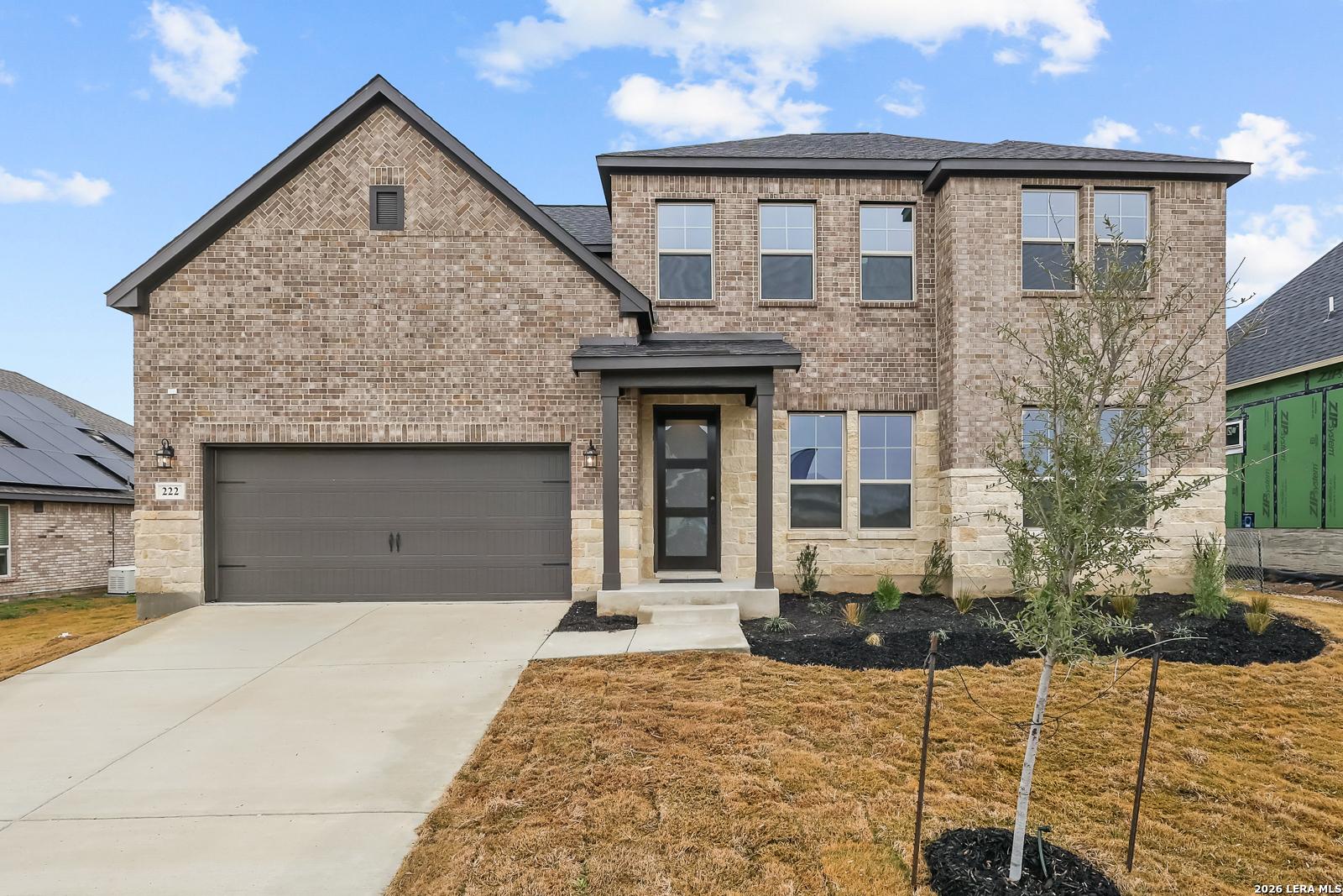 2-story brick Davidson Homes The Belmont G with 2-car garage, driveway, and front landscaping in Castroville, Texas