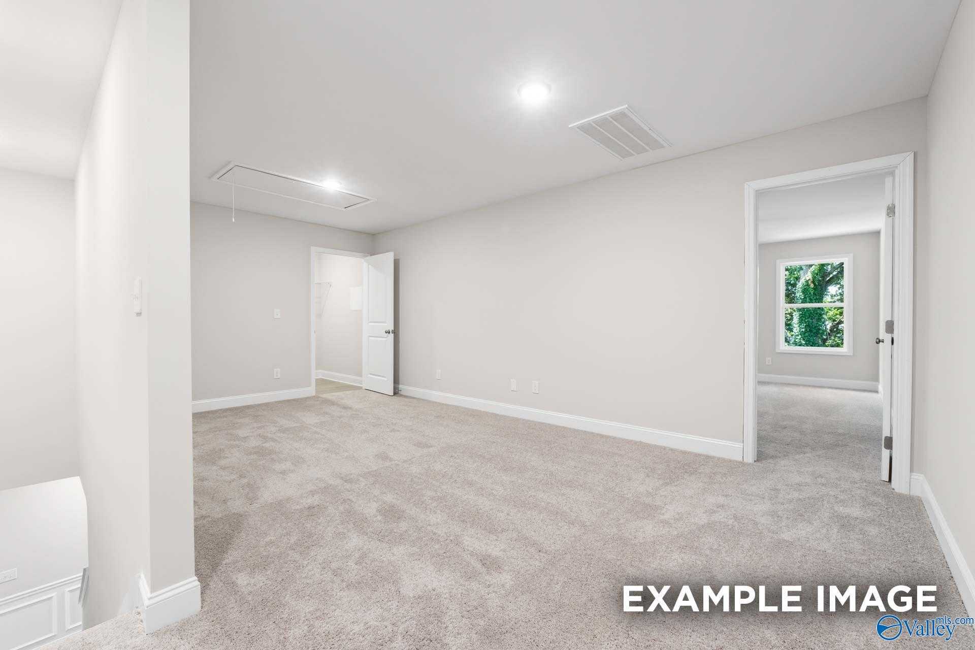 Empty secondary bedroom with beige carpet, white walls, double doors, and window view in Davidson Homes The Camden C, Huntsville AL