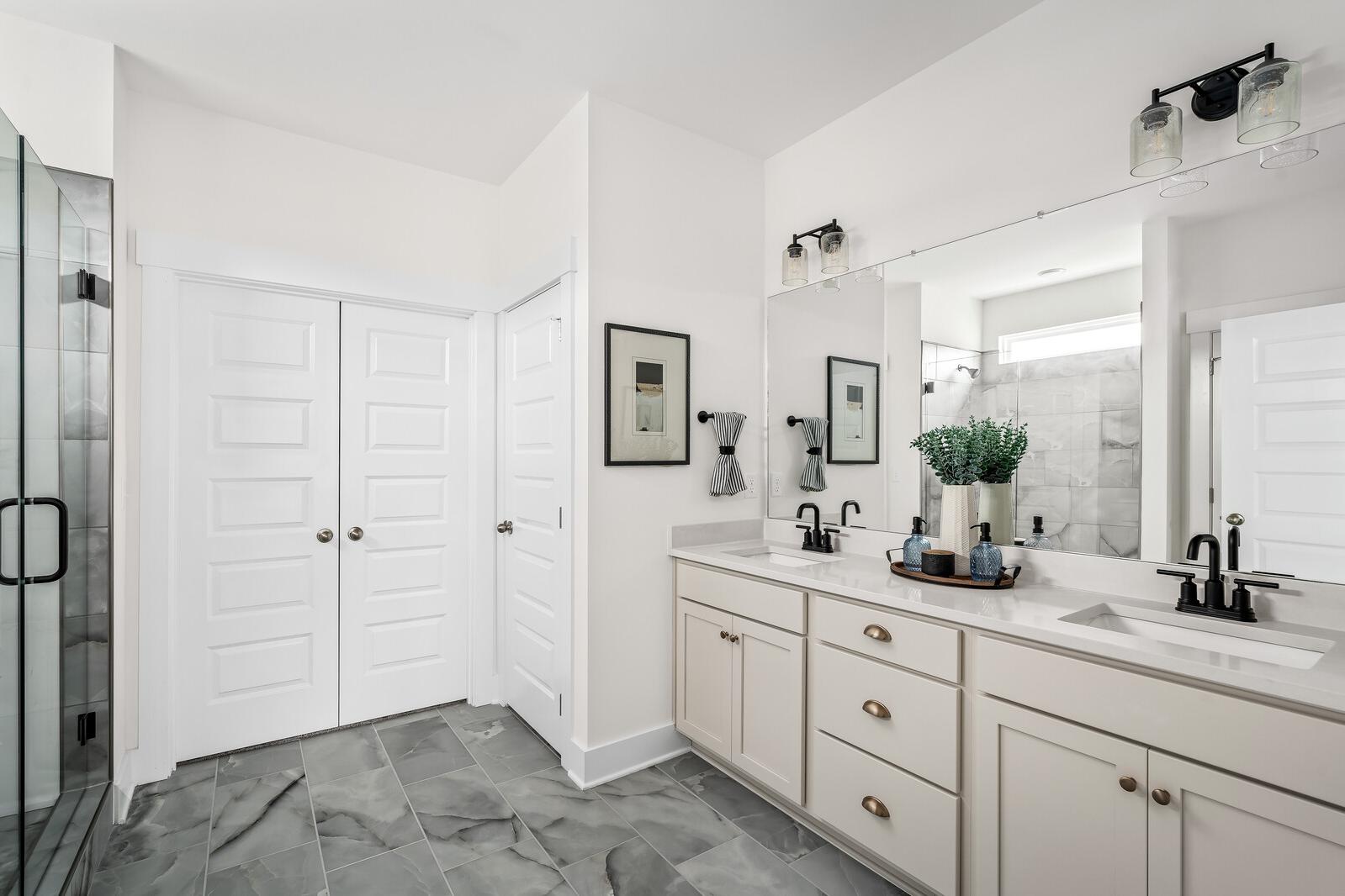 Luxury primary bathroom at Woods Crossing in Gallatin TN with double vanity, glass shower, and shaker cabinets
