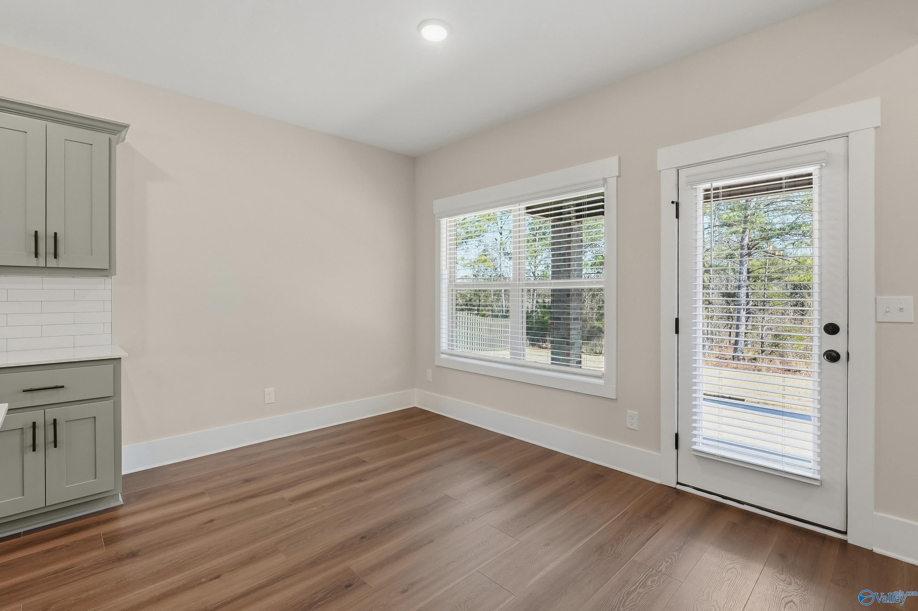 Bright breakfast nook with shaker green cabinets, subway tile backsplash, hardwood floors, large windows, and patio door in Davidson Homes The Shelby A, Athens AL
