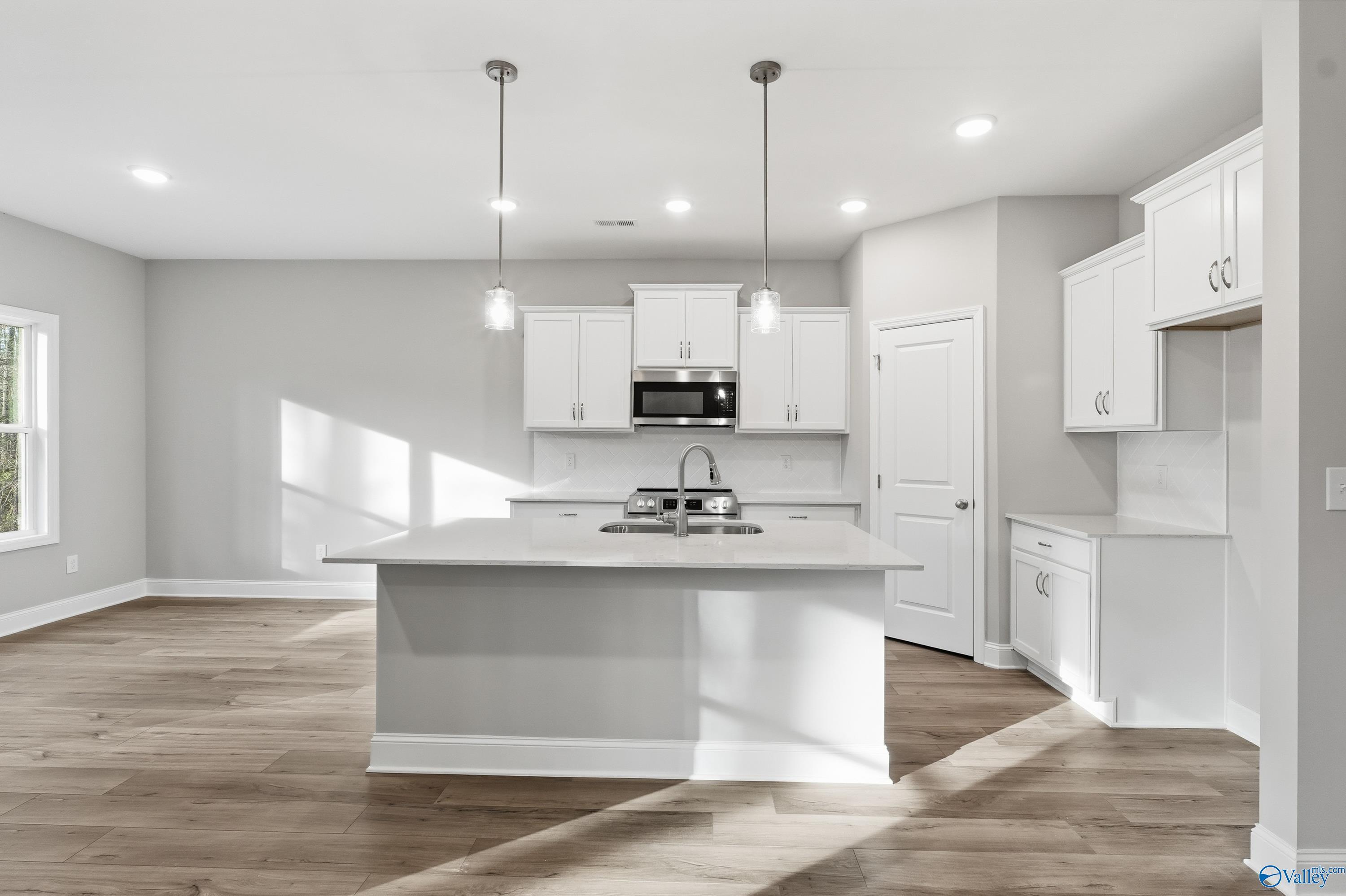 Bright modern kitchen with white island sink, shaker cabinets, pendant lights in The Asheville 3BR home, Davidson Homes, Arab AL