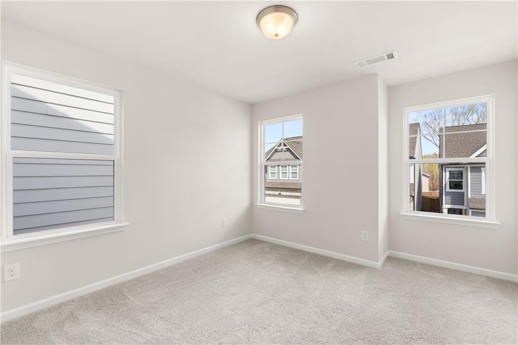 Spacious secondary bedroom with neutral walls, carpet floor, large windows, and neighborhood view in Davidson Homes The Marion B, Kennesaw, GA