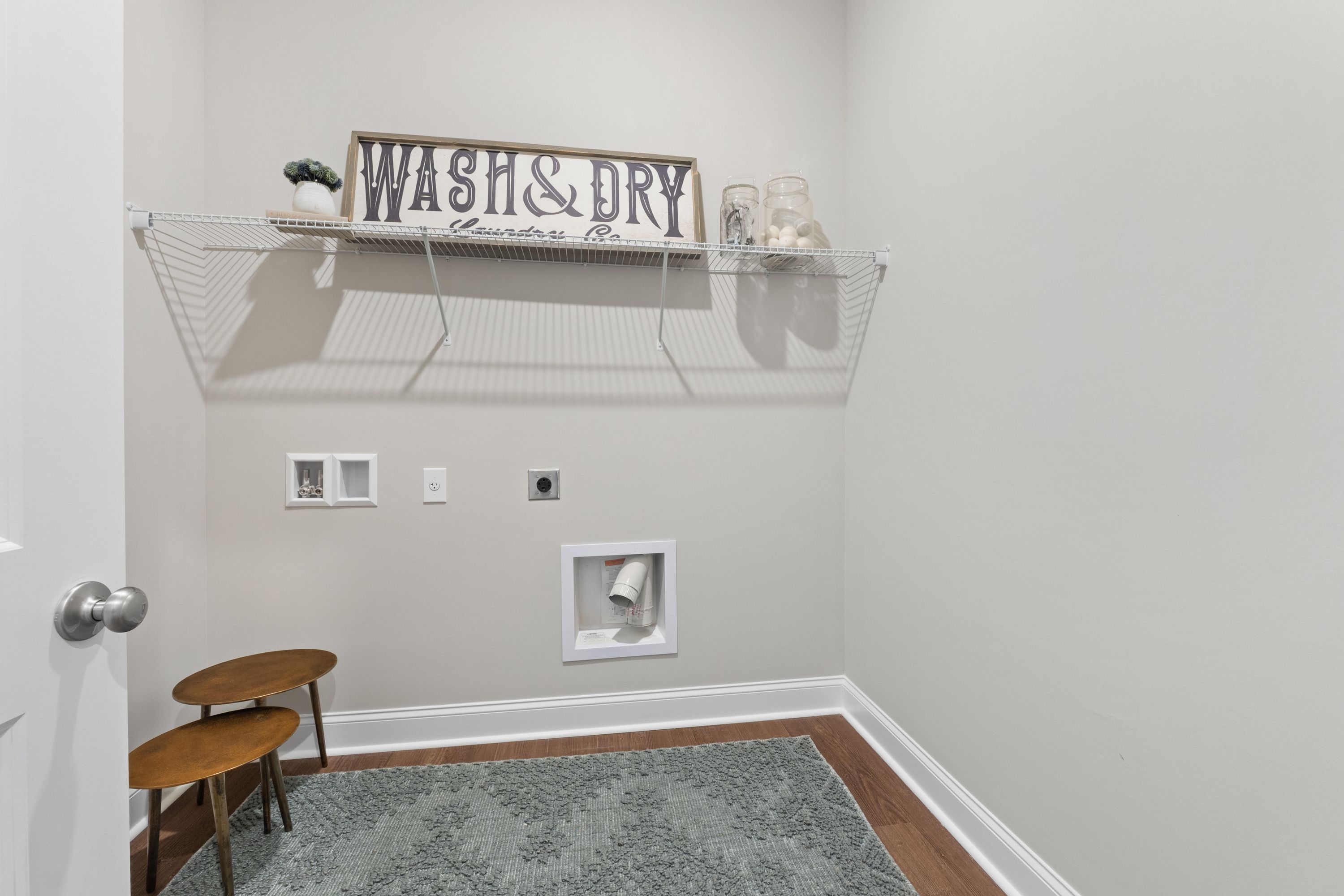 Cozy laundry room in The Haven D home featuring Wash & Dry sign, wire shelving, washer-dryer hookups, and side tables