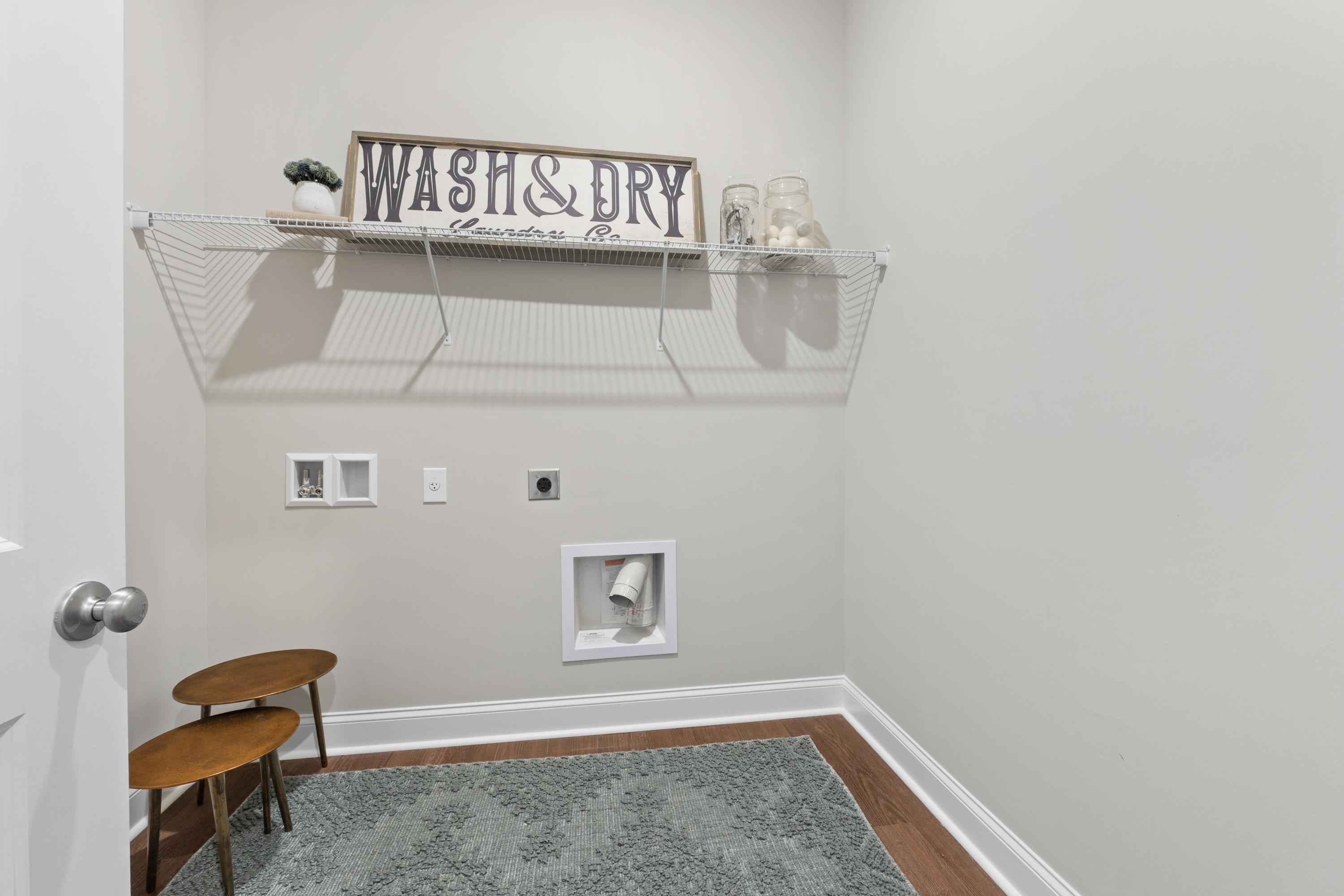 Cozy laundry room in The Haven D home featuring Wash & Dry sign, wire shelving, washer-dryer hookups, and side tables
