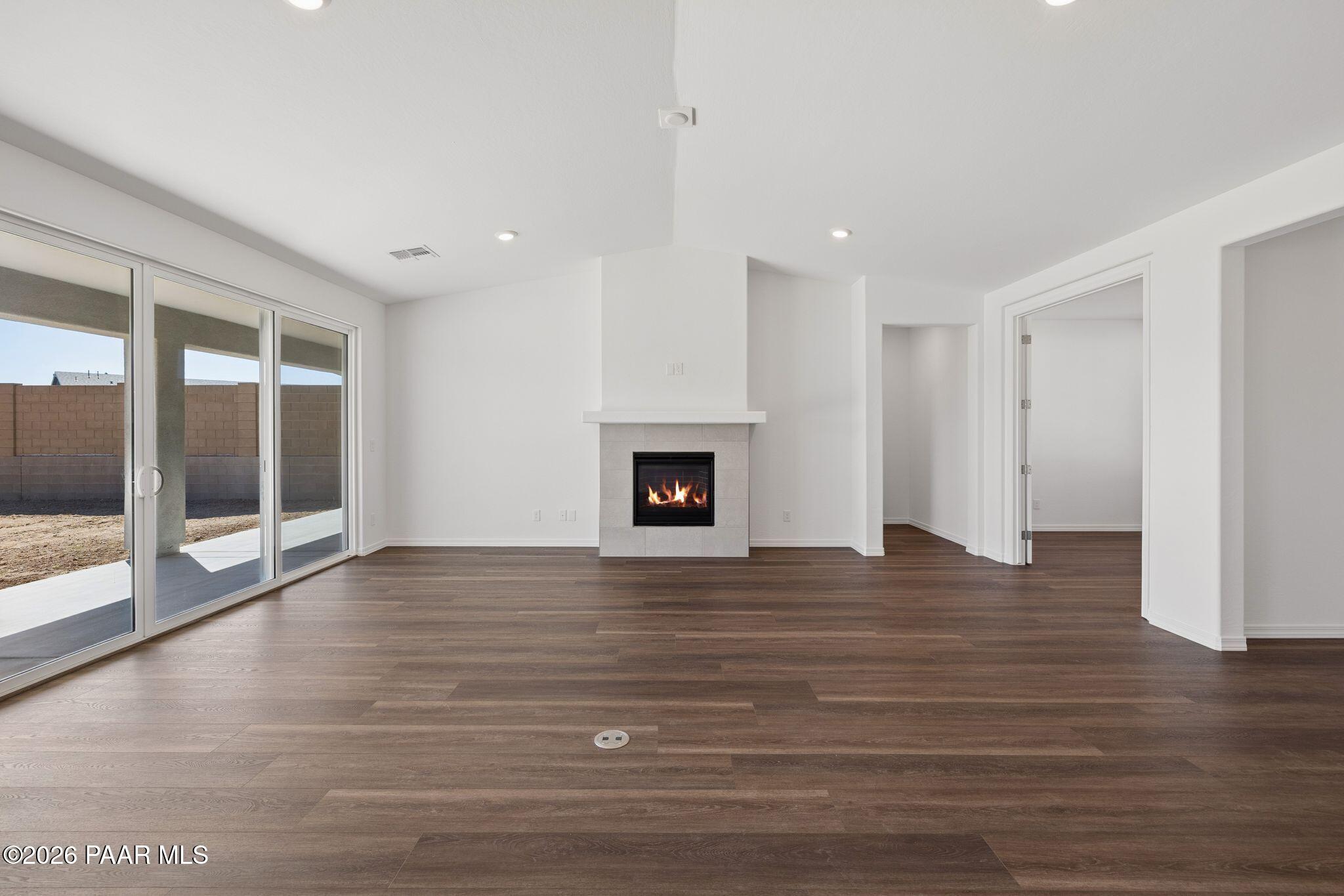 Spacious great room with gas fireplace, hardwood floors, and sliding glass doors to backyard in Davidson Homes The Monarch A, Prescott AZ
