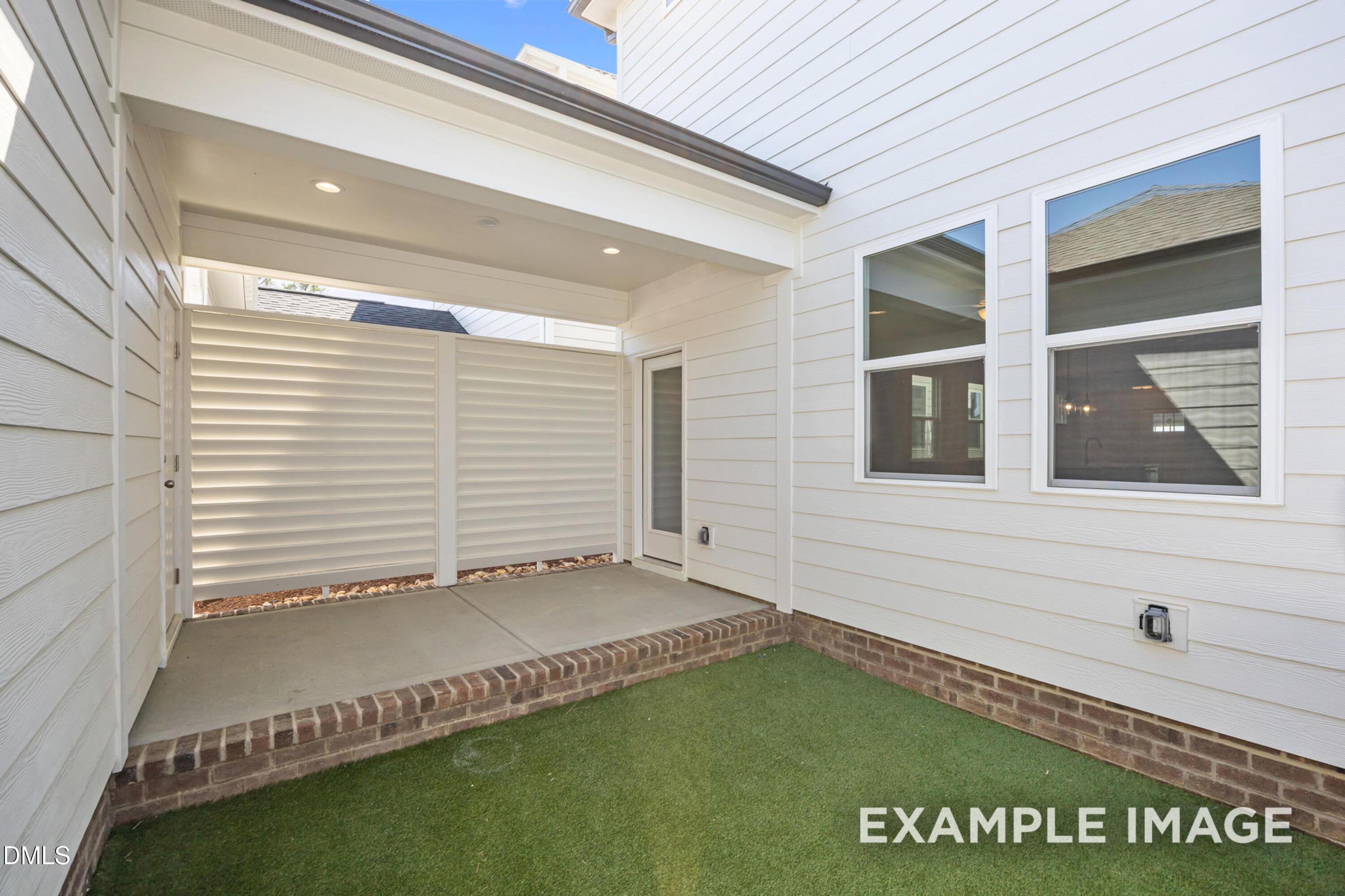 Private covered patio with brick trim and privacy screen at The Alexander B home in Forestville Yard, Knightdale, NC.