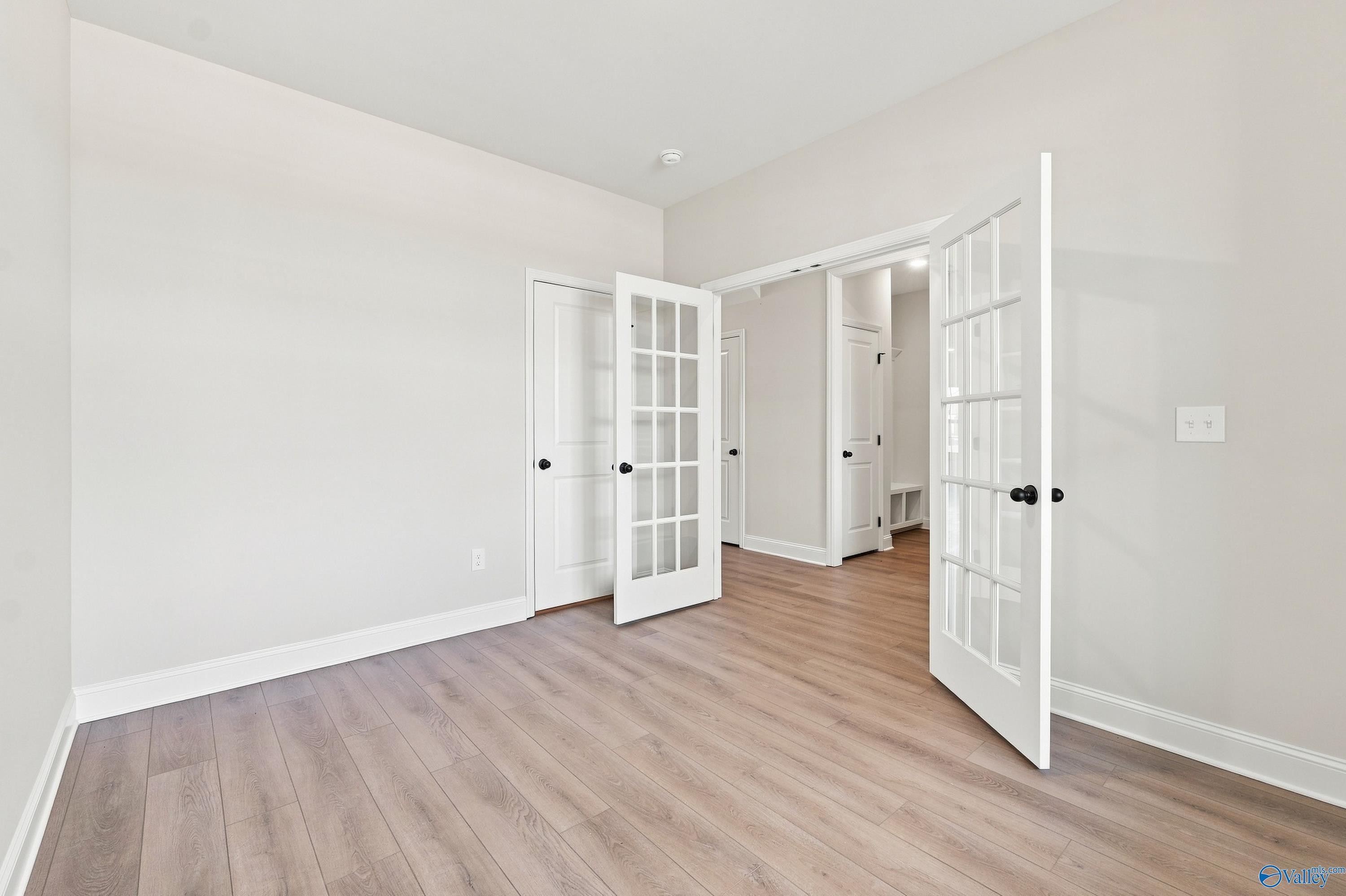 Bright room with elegant French doors and wood-look flooring in The Rockford B floor plan at Kendall Downs, Toney, Alabama.
