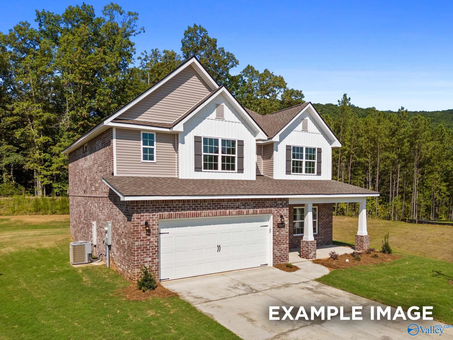 Two-story brick and siding home with two-car garage, front porch, lush lawn, and wooded backdrop in The Highlands, Arab, Alabama