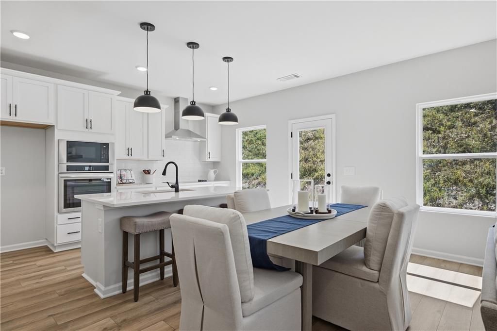 Bright white kitchen with island and pendant lights beside dining area in Davidson Homes Hartwell C plan, The Bluffs, Canton, GA