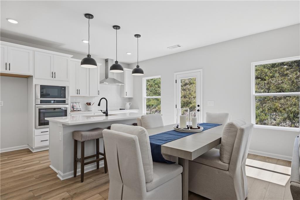 Bright white kitchen with island and pendant lights beside dining area in Davidson Homes Hartwell C plan, The Bluffs, Canton, GA