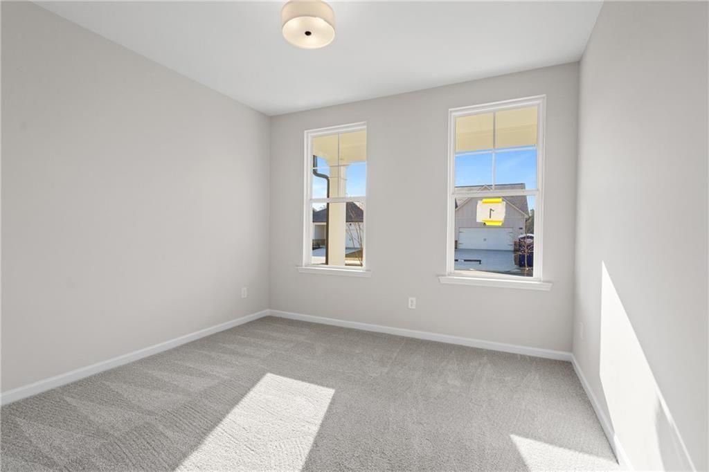 Bright secondary bedroom with gray walls, carpet flooring, and large windows in Davidson Homes The Edison A, Loganville, GA