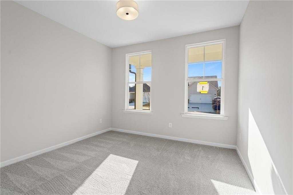 Bright secondary bedroom with gray walls, carpet flooring, and large windows in Davidson Homes The Edison A, Loganville, GA