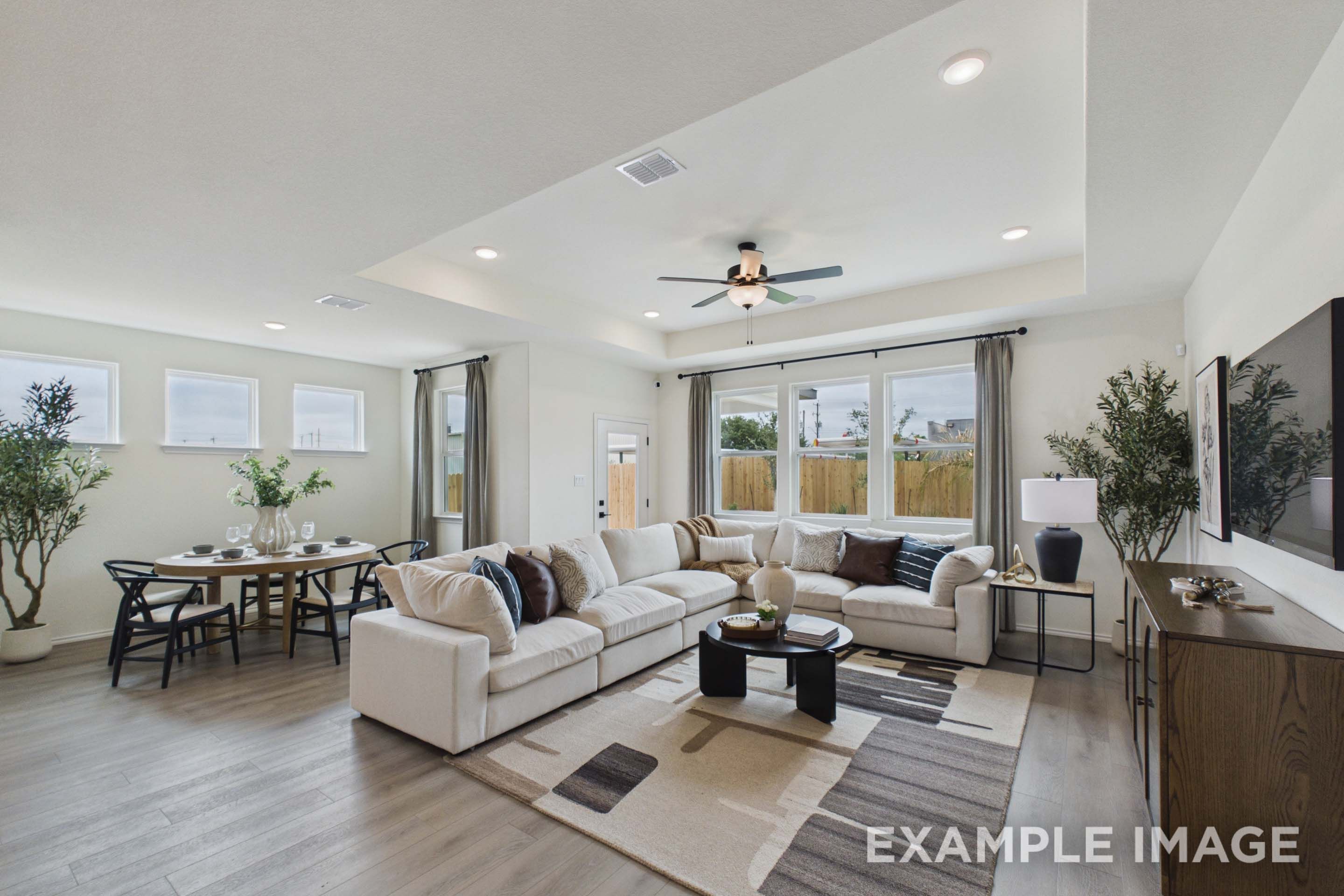 Open-concept living and dining area in The Laurel G featuring a tray ceiling, spacious sectional, and modern decor.