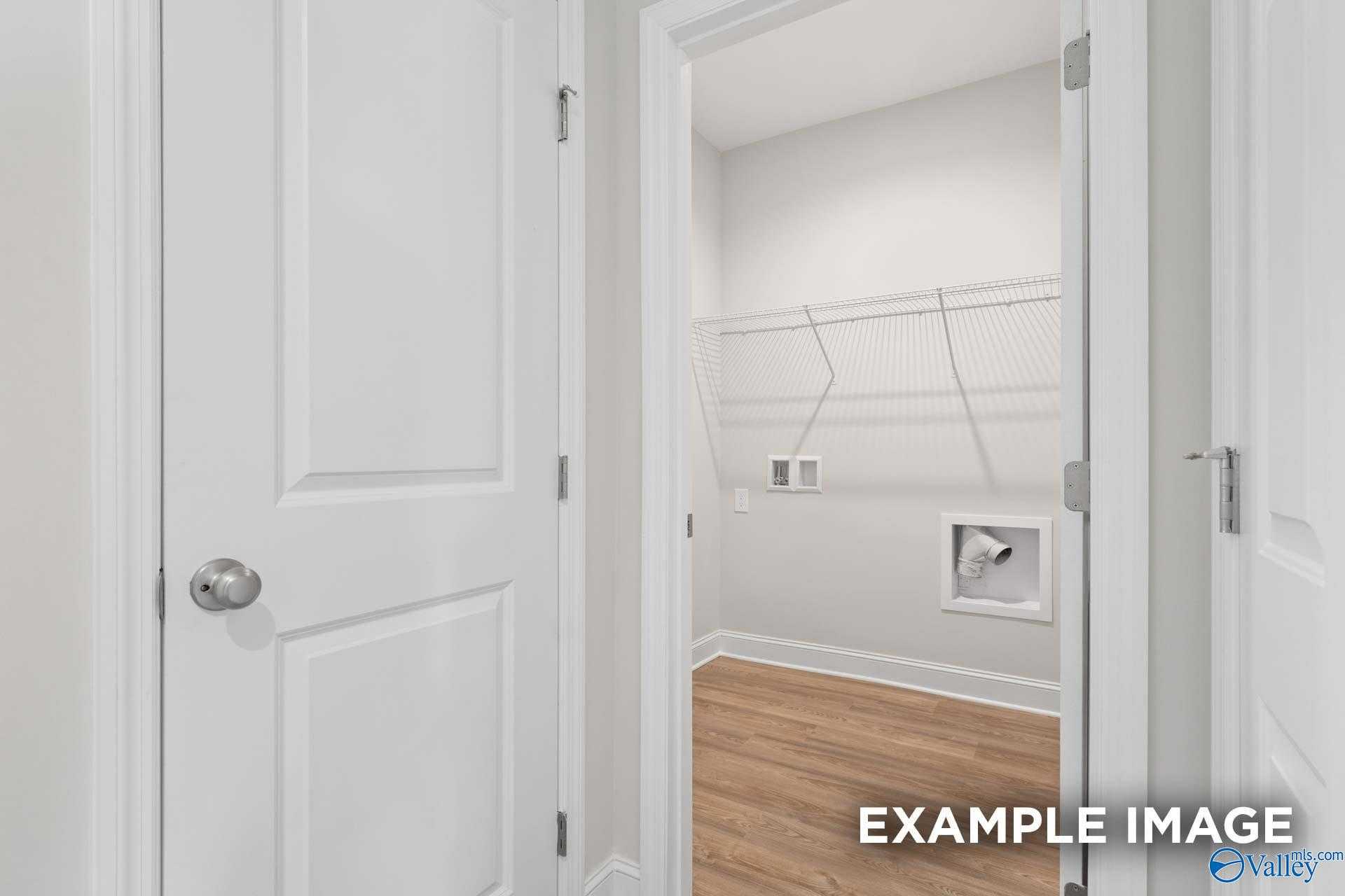 Spacious laundry room with white shelving, washer/dryer hookups, and hardwood floors in Davidson Homes The Franklin C, Meridianville, Alabama