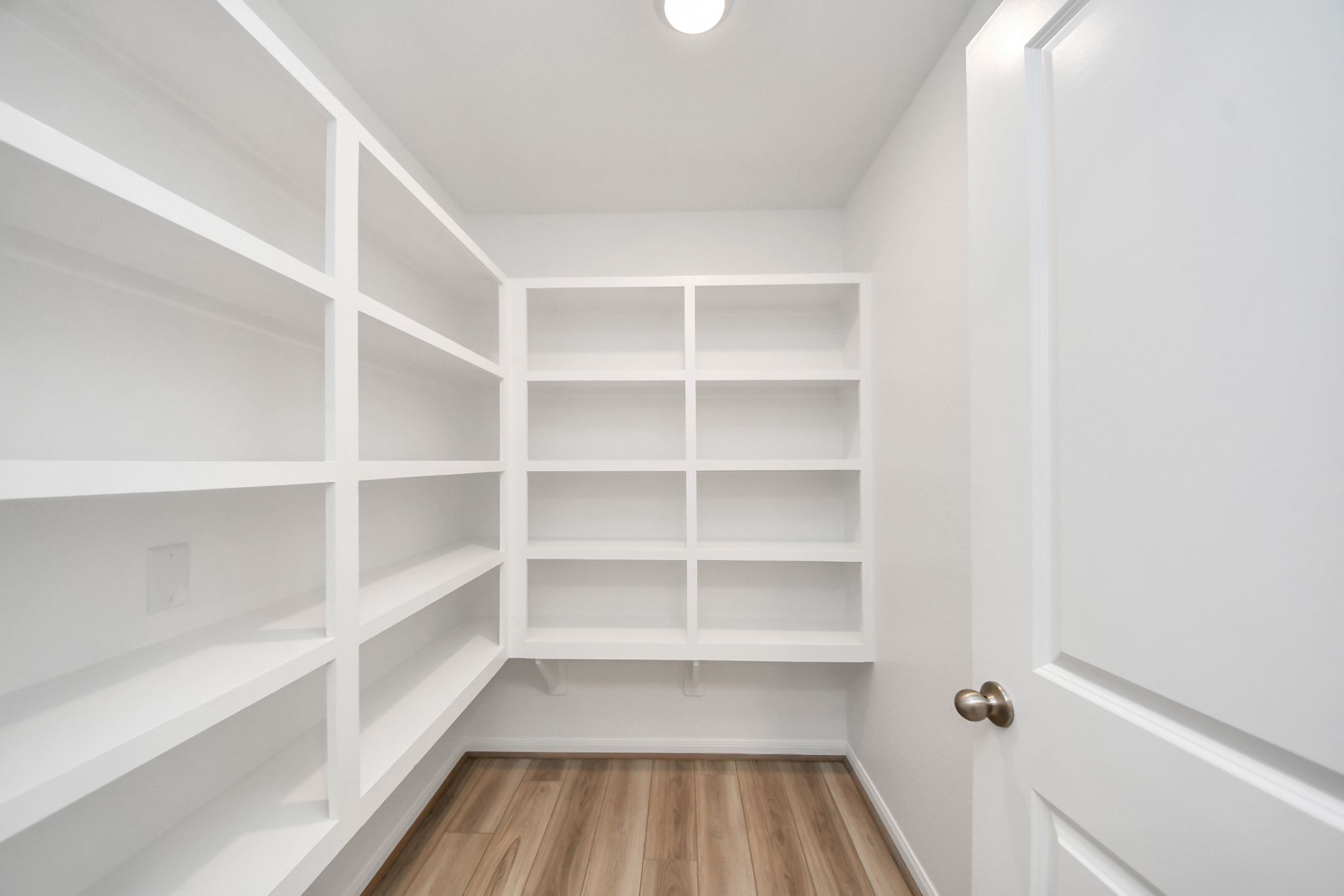 Spacious walk-in pantry with white built-in shelving at Sunterra in Katy, Texas by Davidson Homes.