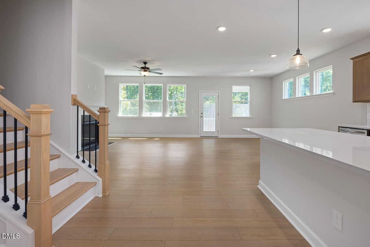 Open-concept living area with fireplace, hardwood floors, and kitchen island in The Ashport L, Wake Forest, North Carolina.
