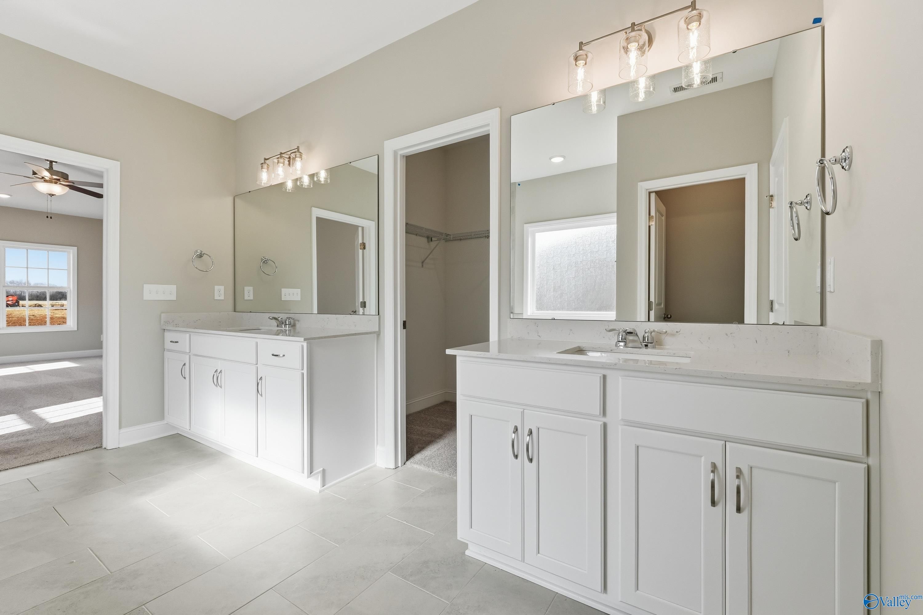 Elegant master bathroom with double white vanity, mirrors, and soft lighting in The Lanier by Davidson Homes, Meridianville, AL