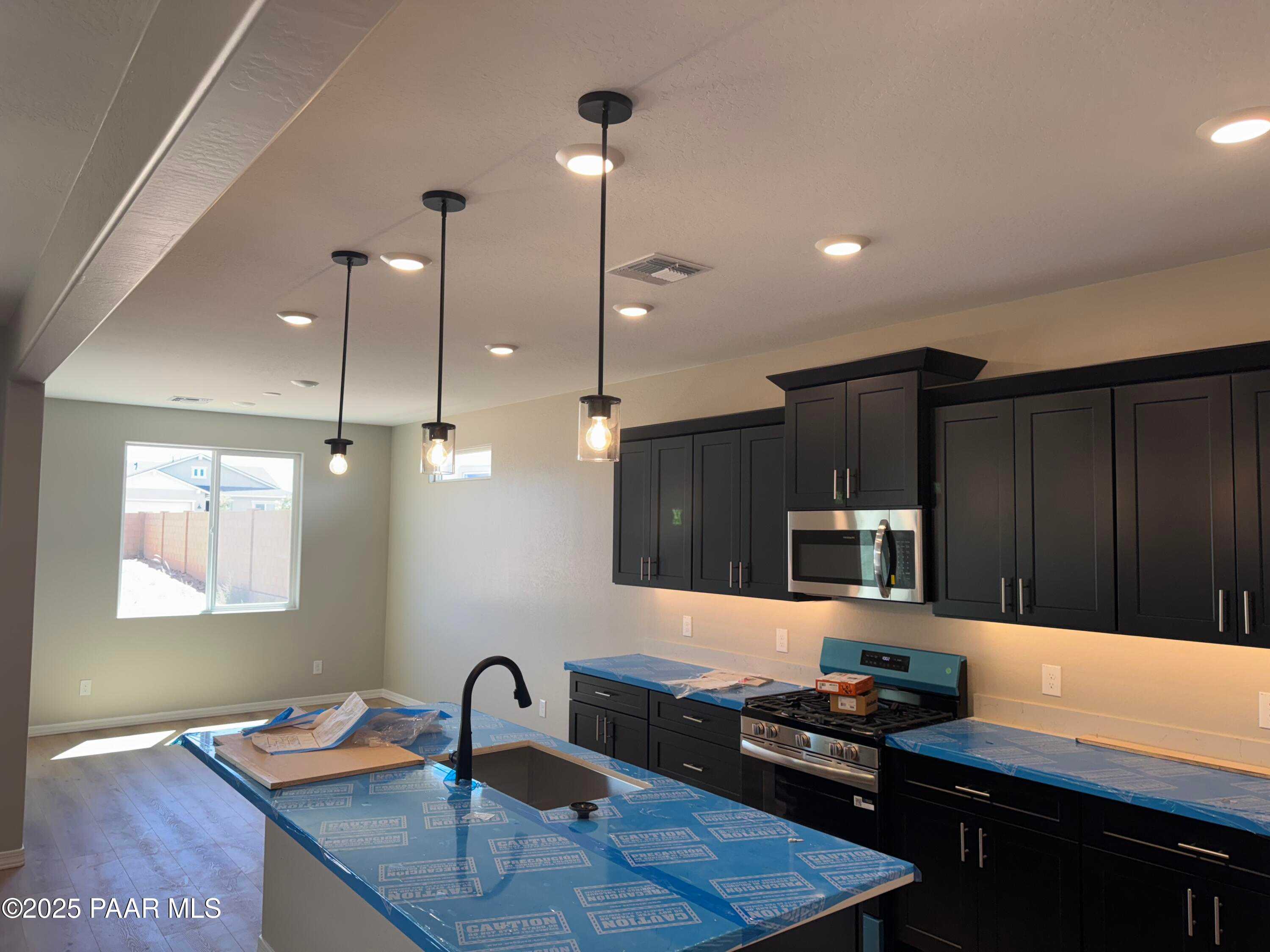 Modern kitchen with black shaker cabinets, stainless appliances, pendant lights, and center island in Davidson Homes Sheridan II B, Prescott AZ