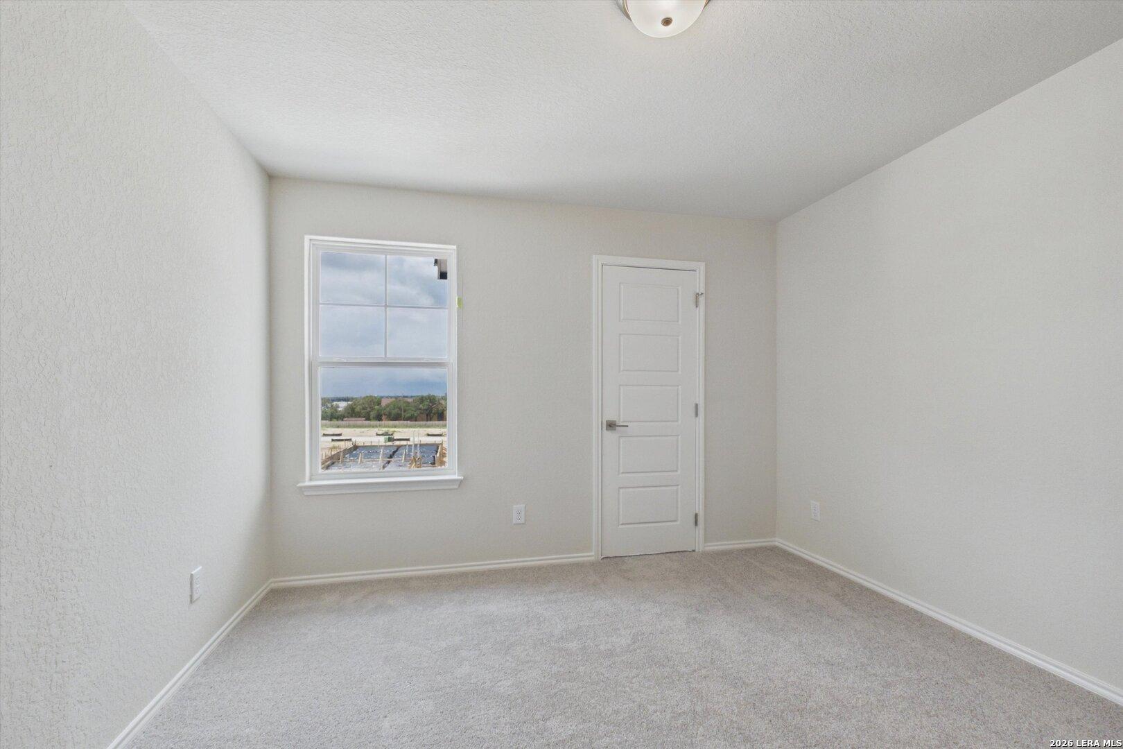 Bright, neutral-toned bedroom in The Charlotte B floor plan by Davidson Homes at Meadows at Oak Creek, San Antonio.