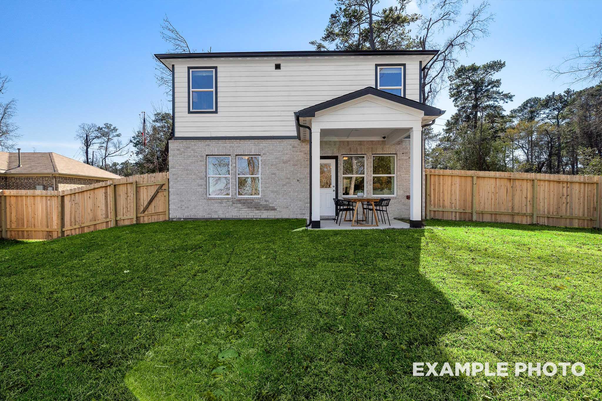 Rear view of The San Marcos 5-bedroom two-story home by Davidson Homes, featuring covered patio, fenced yard, and lush green lawn