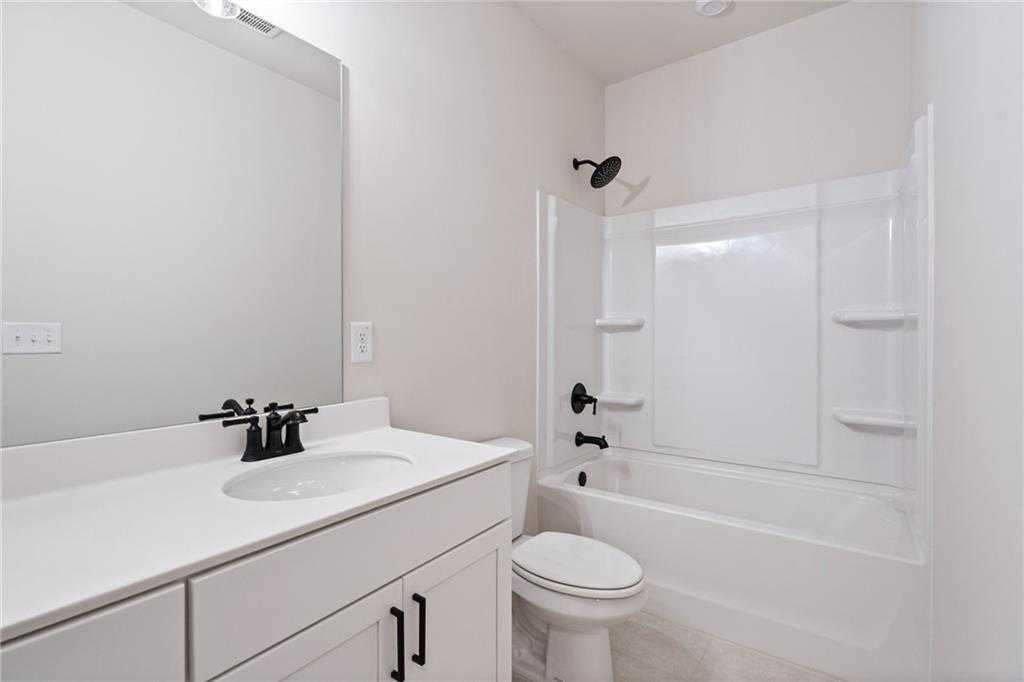 Modern bathroom with white vanity, black fixtures, bathtub shower combo in Davidson Homes The Glenwood C, Loganville, GA