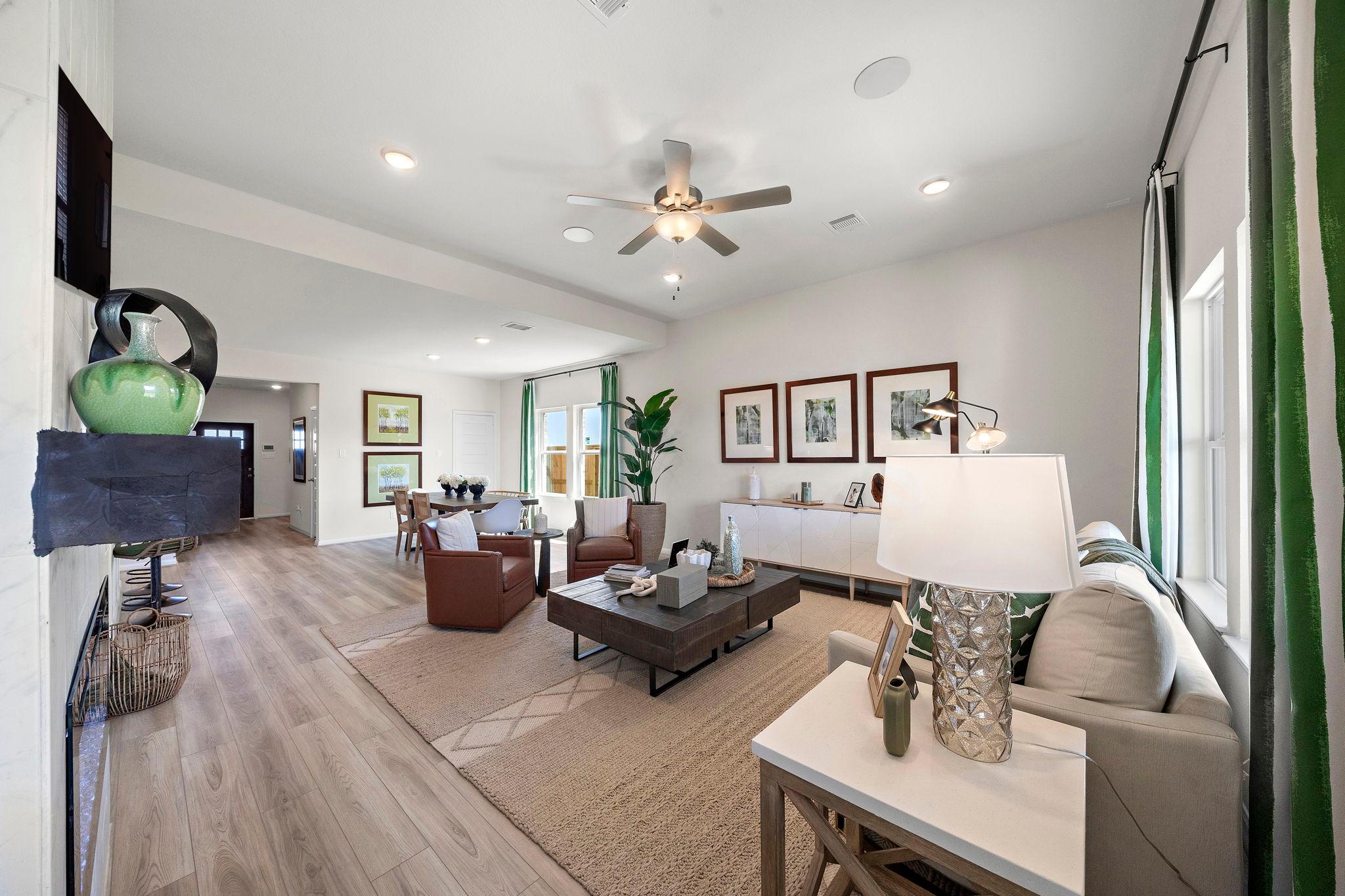 Spacious open-concept living room at River Ranch Meadows in Dayton Texas with hardwood floors, leather seating, ceiling fans