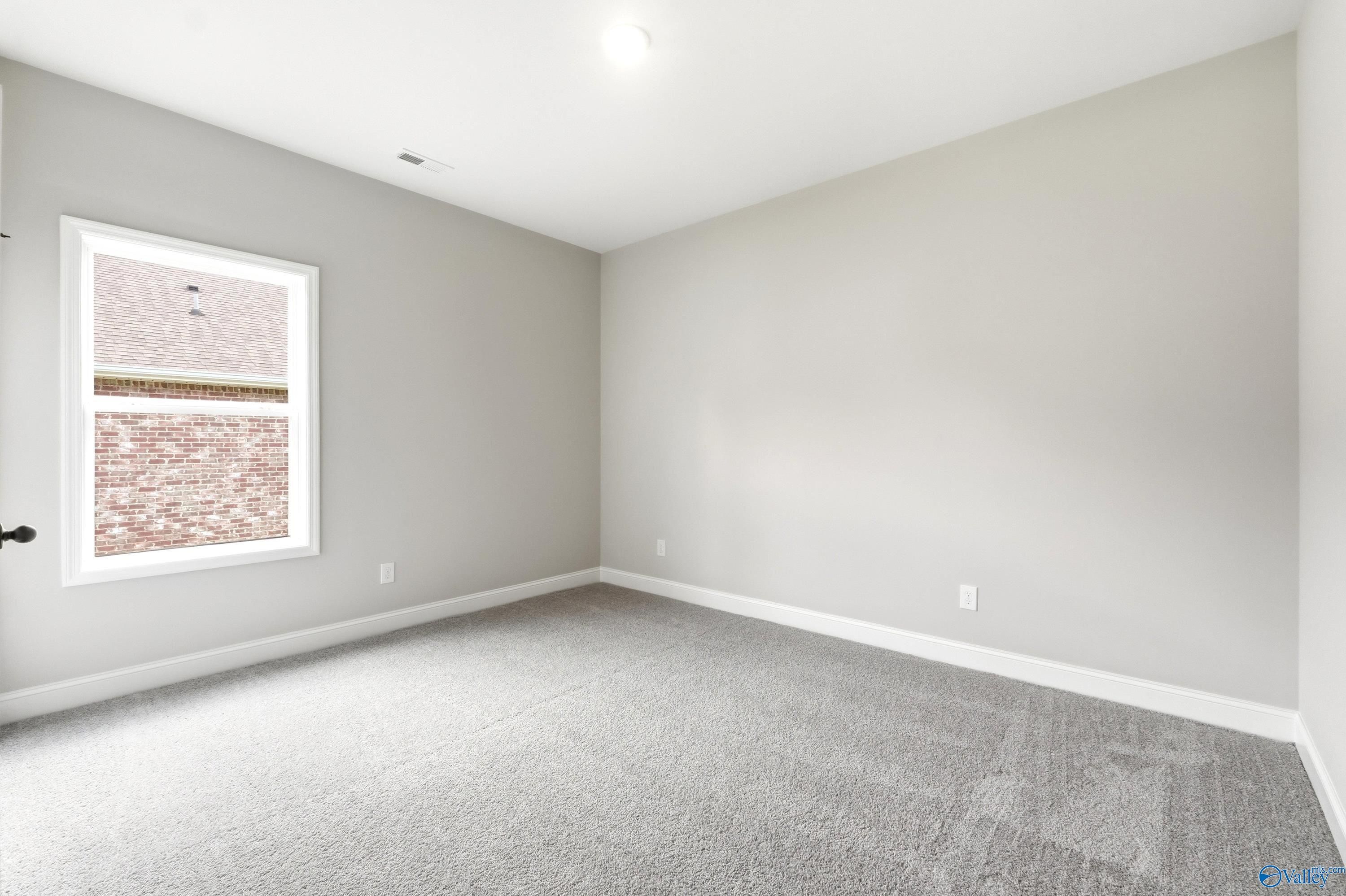 Spacious bedroom with neutral paint and plush carpet in The Daphne C floor plan at Flint Meadows, New Market, Alabama.