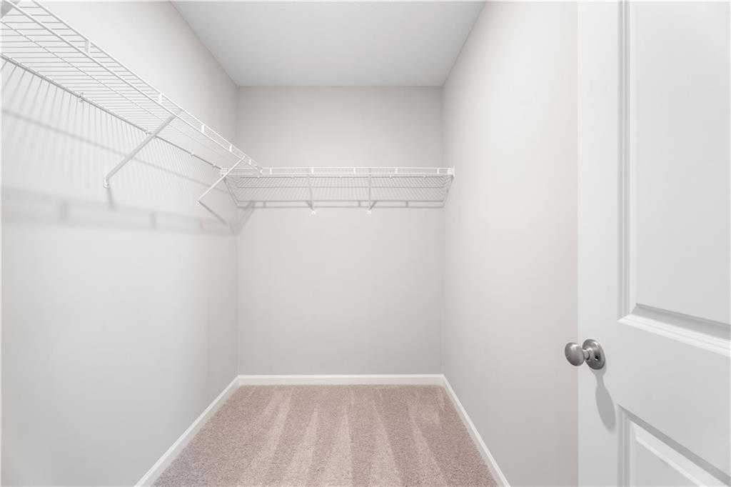 Spacious walk-in closet featuring wire shelving, white walls, and carpet floor in Davidson Homes The Washington, Phenix City, Alabama