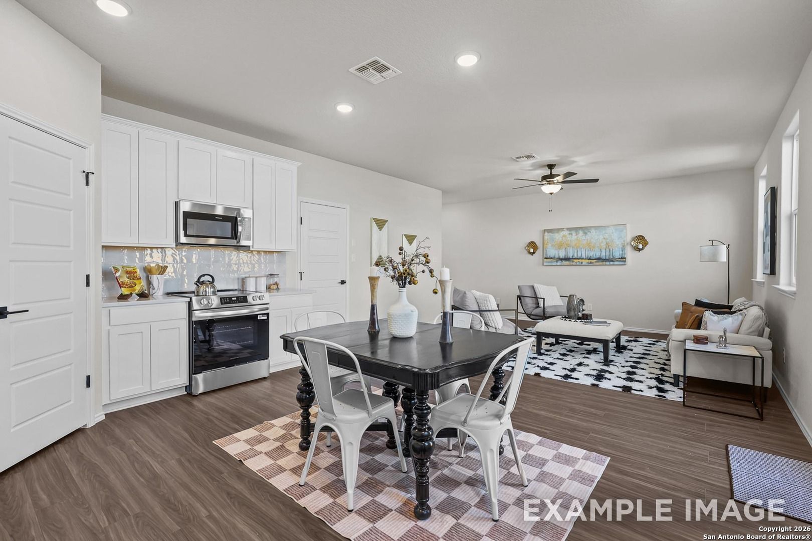 Bright open-concept kitchen and dining in The Trinity B floor plan, white cabinets, stainless appliances, black table, San Antonio home