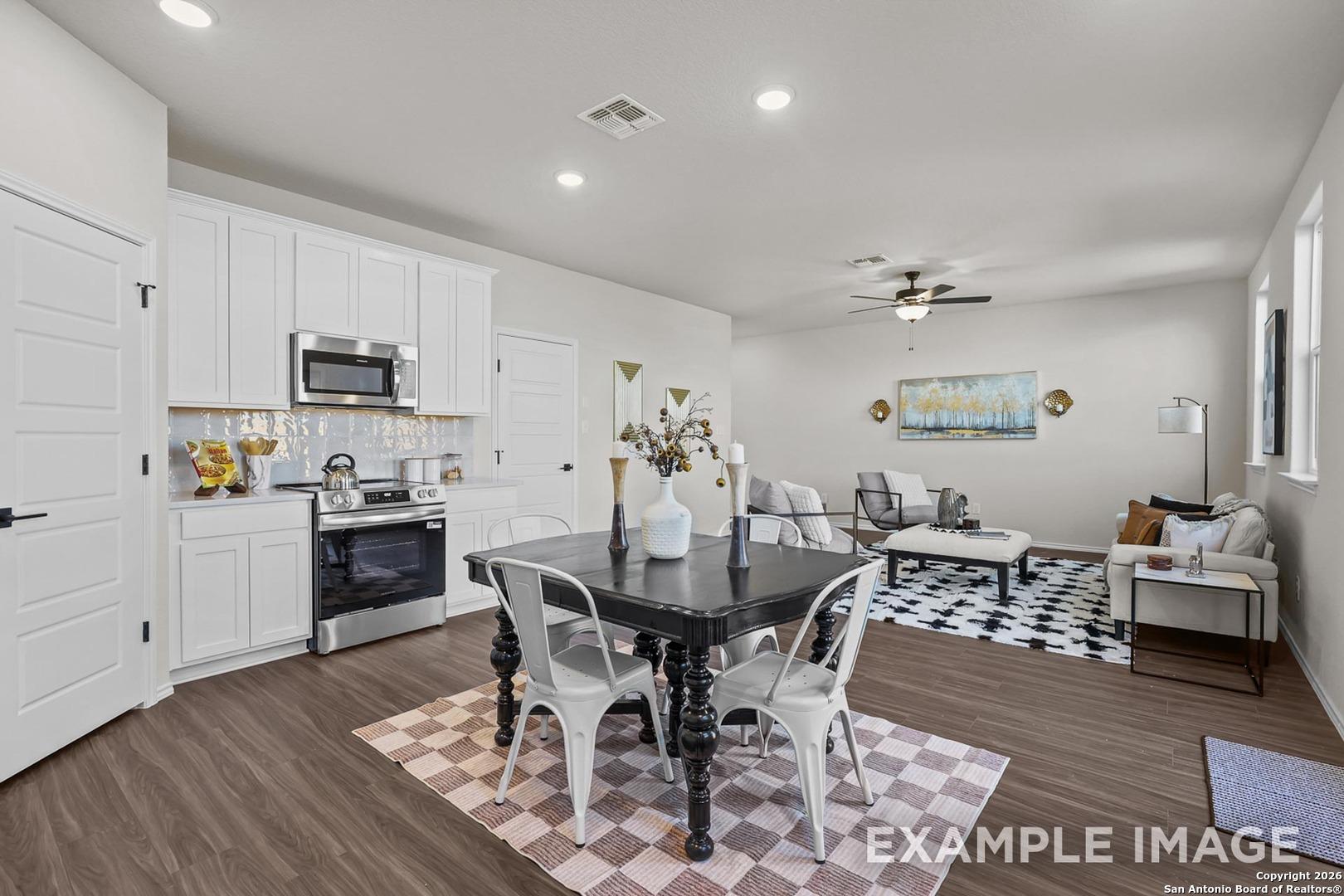 Bright open-concept kitchen and dining in The Trinity B floor plan, white cabinets, stainless appliances, black table, San Antonio home